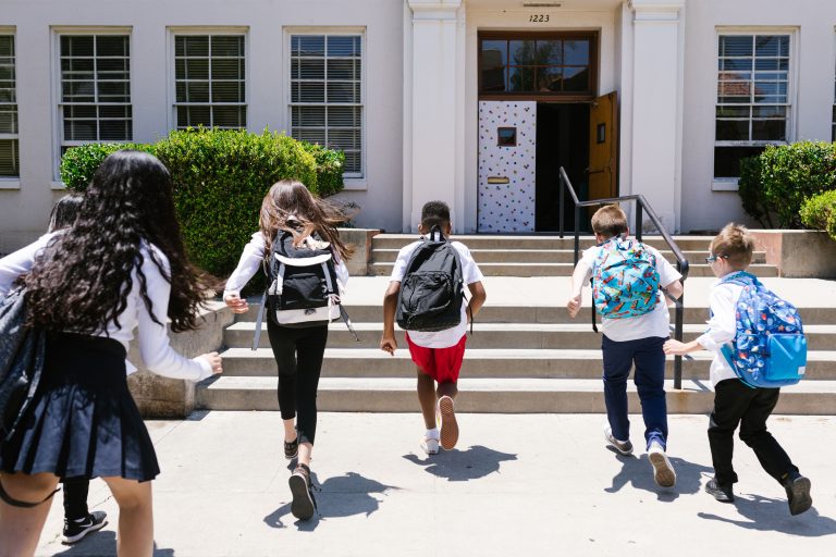 Back view shot of students running to their classroom